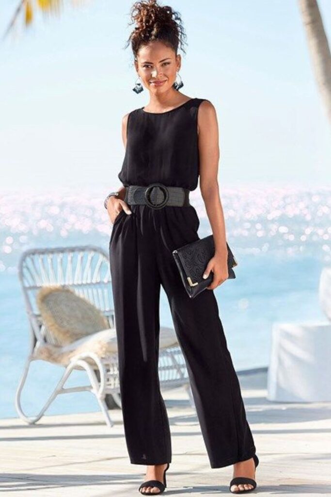 A Petite Woman Wearing Black Jumpsuit With A Structured Handbag
